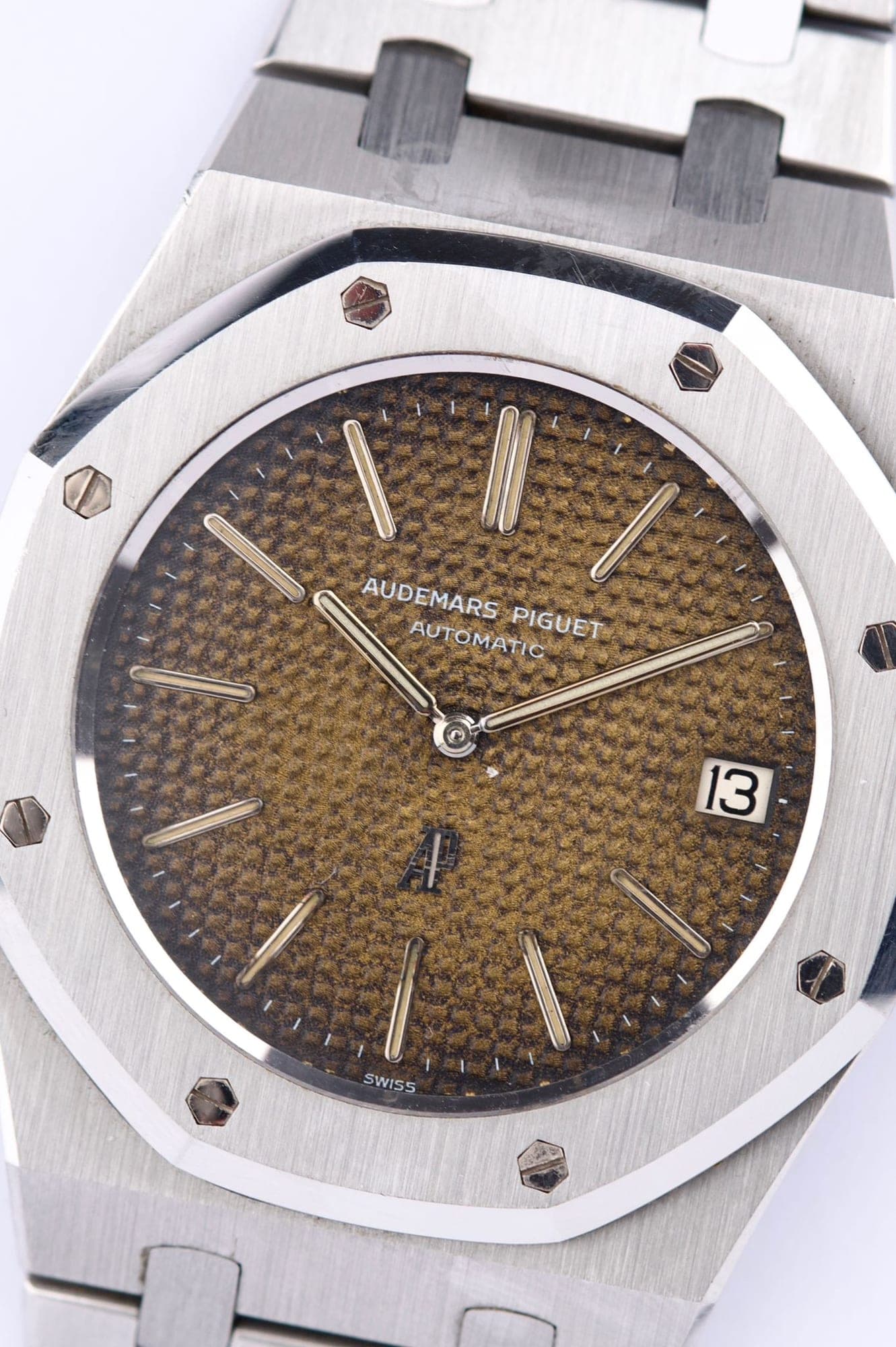 Close-up of an Audemars Piguet Royal Oak dial with a faded brown tapisserie pattern, baton hour markers and date window